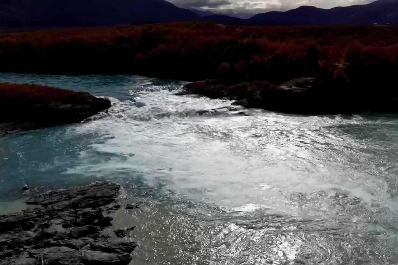 Preserve: glacial meltwater running between rock and autumn scrub.